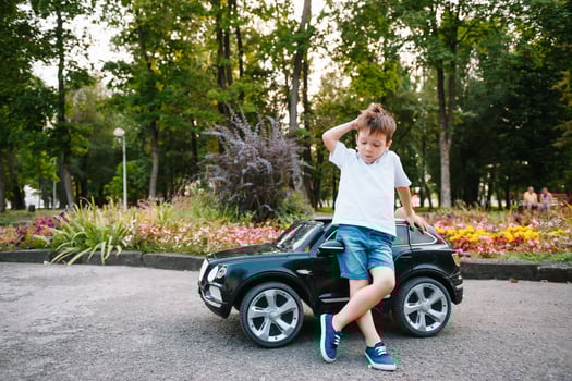 Cute boy in riding a black electric car in the park. Funny boy rides on a toy electric car. Copy space. photo