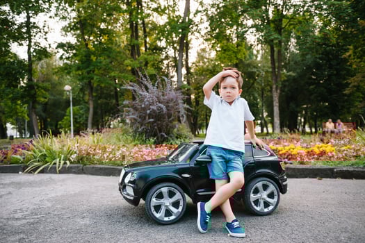 Cute boy in riding a black electric car in the park. Funny boy rides on a toy electric car. Copy space. photo