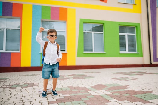 Back to school. Happy smiling boy in glasses is going to school for the first time. Child with backpack and book outdoors. Beginning of lessons. First day of fall photo