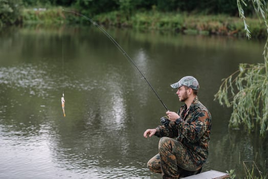 Fishing in river.A fisherman with a fishing rod on the river bank. Man fisherman catches a fish pike.Fishing, spinning reel, fish, Breg rivers. - The concept of a rural getaway. Article about fishing photo