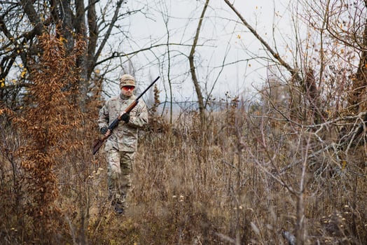 Hunter handsome guy with weapon. Hunter spend leisure hunting. Hunting equipment. Brutal masculine hobby. Man observing nature background. Hunter hold rifle. Safety measures. Natural environment photo