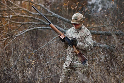 Hunter handsome guy with weapon. Hunter spend leisure hunting. Hunting equipment. Brutal masculine hobby. Man observing nature background. Hunter hold rifle. Safety measures. Natural environment photo