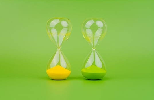 Green and yellow hourglass on a light green background, rules of time and countdown time process. photo