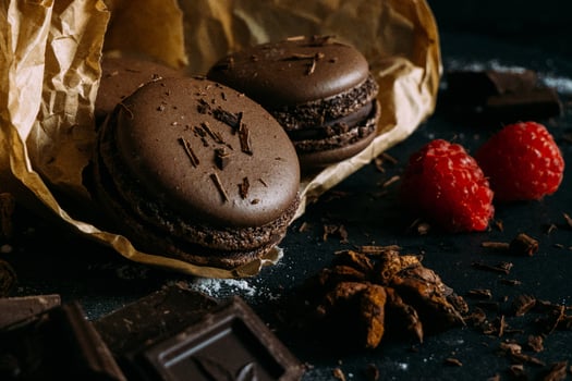 chocolate macarons with raspberries on a dark background photo