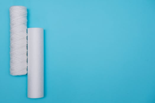 Water filters. Carbon cartridges and a glass with water on a blue background. Household filtration system. photo