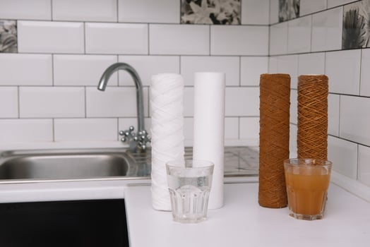 Water filter cartridge used and a glass of rusty water brown coloring and new filter and a glass of clean water. Evidence of contamination of tap water with iron cations. white kitchen. photo