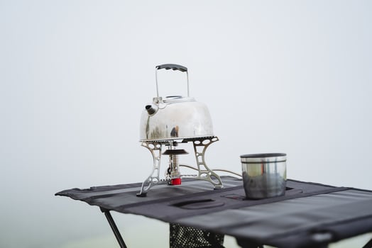 Gas tourist burner, kettle stands on the burner, a glass for hot drinks, tourist dishes for hiking, compact equipment. photo