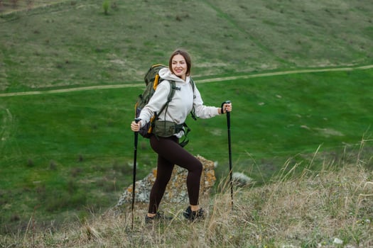 Young woman with backpack hiking in the mountains. Hiking concept. Trekking cliffs. Travel, traveler. photo
