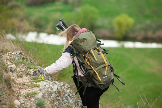 Young woman with backpack hiking in the mountains. Hiking concept. Trekking cliffs. Travel, traveler. photo