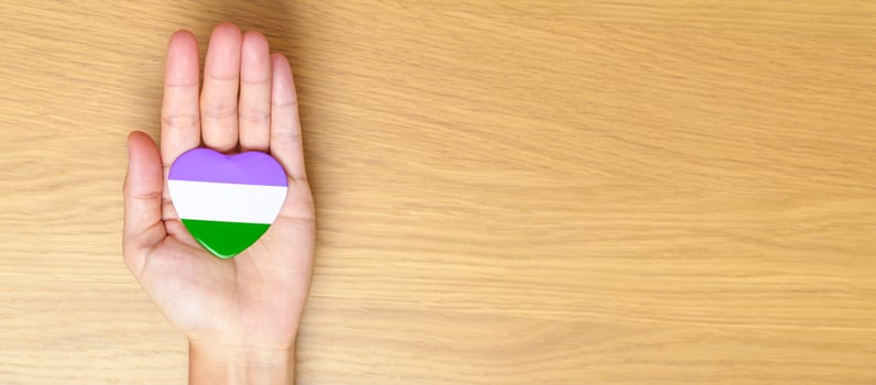 Queer Pride Day and LGBT pride month concept. hand holding purple, white and green heart shape for Lesbian, Gay, Bisexual, Transgender, genderqueer and Pansexual community photo