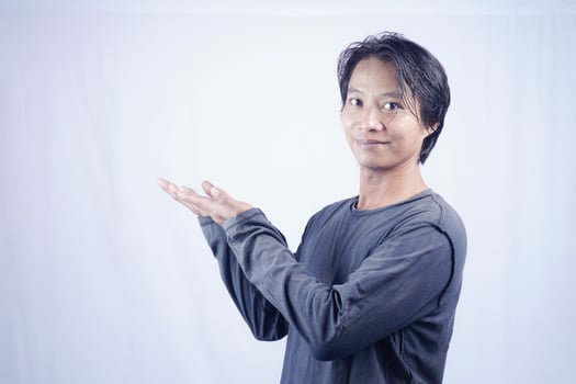 Handsome Asian man facing the camera is pointing at the copy space for advertising on an isolated white background. photo