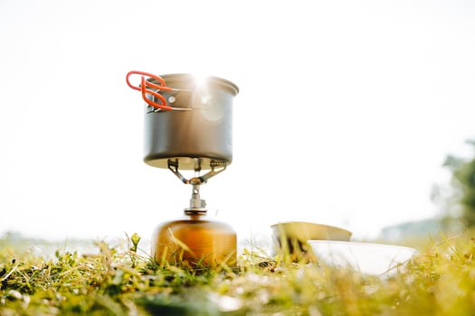 Utensils on a camping trip to cook on a burner, glare of sunlight shine through a pot, trekking through the mountains, cooking soup in nature, a solo hike. photo