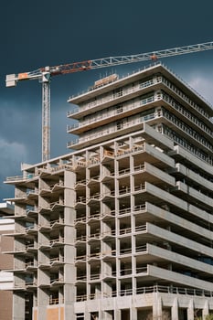 Tower crane above an apartment building under construction against a stormy sky photo