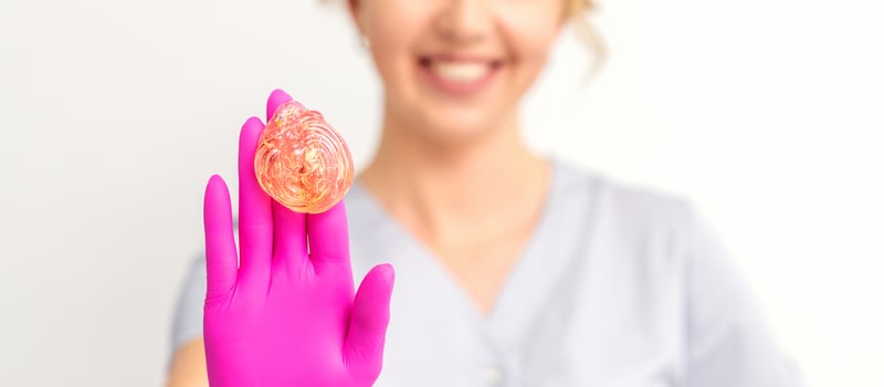 Yellow sugar paste in hand master of depilation. Smiling beautician holding wax for depilation over white background. Concept epilation. photo