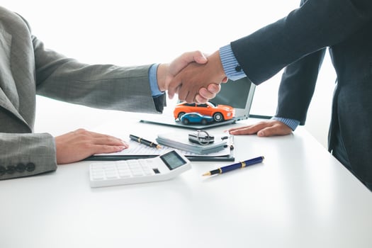 customer and car dealer shake hands after agreeing to sales contract before making contract payment and handing over car keys to customer. concept of handshake between customers and car dealers. photo