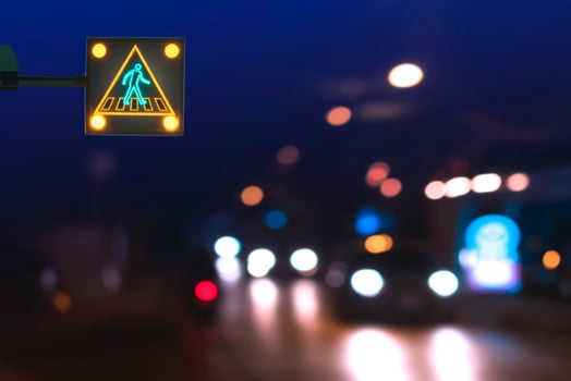 Illuminated electric traffic light pedestrian crossing sign with blurred night city street background photo