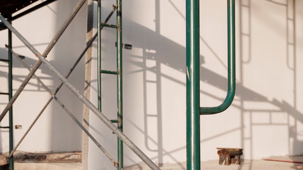 Focus at green scaffolding with blurred light and shadow on concrete wall surface inside of house construction site photo