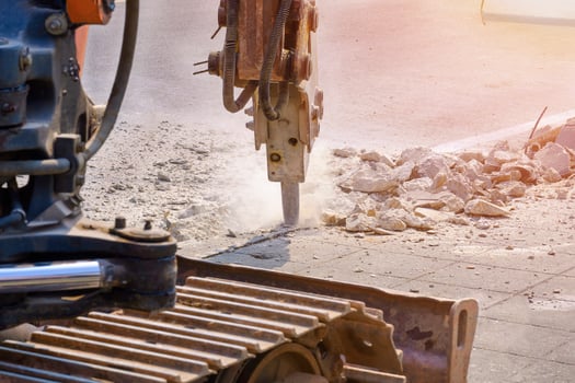 Selective focus at the old excavator hydraulic crushing hammer is breaking pavement on roadside area for preparing to install sewer system work photo