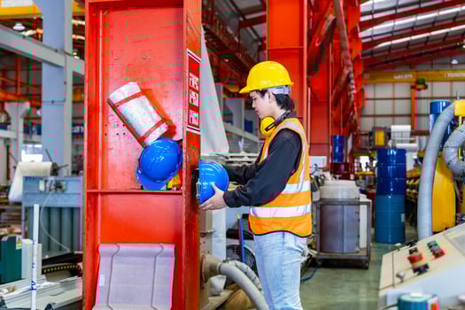 Asian worker is hanging his safety helmet on the rack inside the heavy industrial factory for protection and accident prevention concept photo