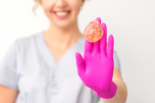 Yellow sugar paste in hand master of depilation. Smiling beautician holding wax for depilation over white background. Concept epilation. photo