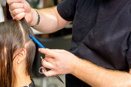 Hairdresser divides female hair into sections with comb holding hair with her hands in hair salon close up. photo