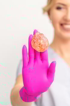 Yellow sugar paste in hand master of depilation. Smiling beautician holding wax for depilation over white background. Concept epilation. photo
