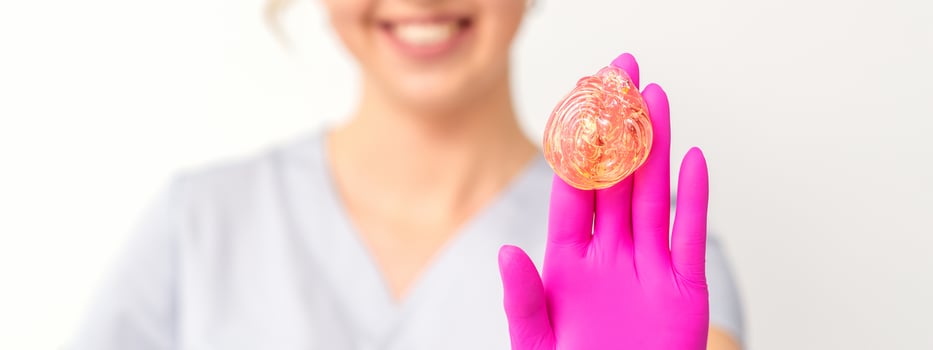 Yellow sugar paste in hand master of depilation. Smiling beautician holding wax for depilation over white background. Concept epilation. photo