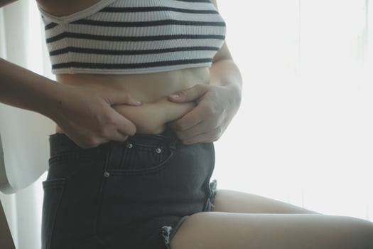 Women body fat belly. Obese woman hand holding excessive belly fat. diet lifestyle concept to reduce belly and shape up healthy stomach muscle. photo