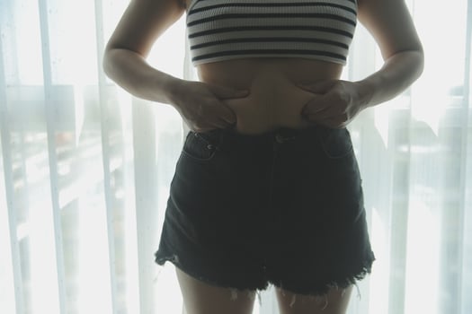 Women body fat belly. Obese woman hand holding excessive belly fat. diet lifestyle concept to reduce belly and shape up healthy stomach muscle. photo