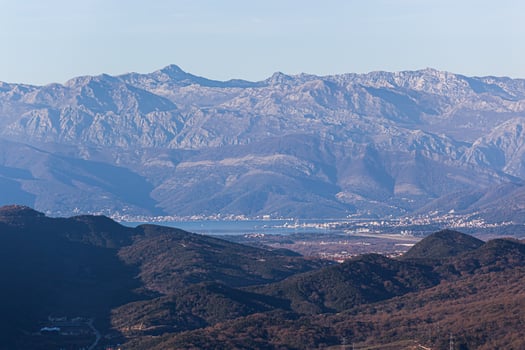 Picturesque panoramic view of the city, sea and mountain range under blue skies across green hills in summer. Background. For text. Banner. Postcard. Horizontal photo