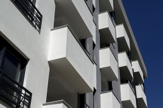 White apartment building against clear blue sky. Isometric photo of balconies