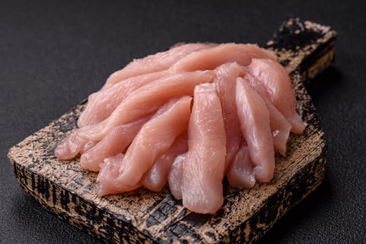 Slices of raw chicken or turkey fillet with salt, spices and herbs photo