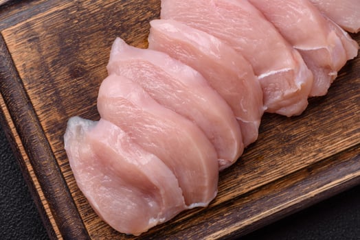 Slices of raw chicken or turkey fillet with salt, spices and herbs photo