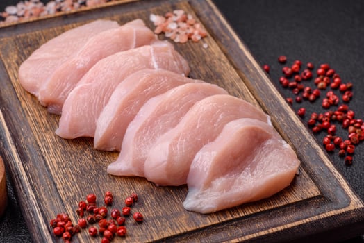 Slices of raw chicken or turkey fillet with salt, spices and herbs photo