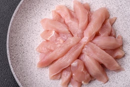 Slices of raw chicken or turkey fillet with salt, spices and herbs photo