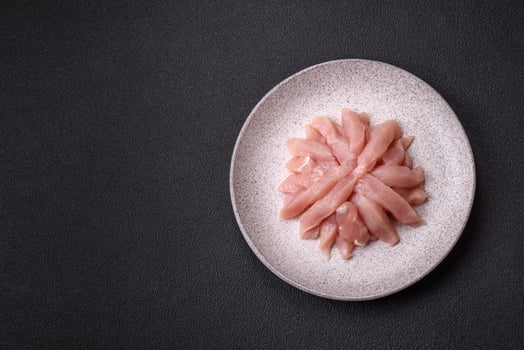 Slices of raw chicken or turkey fillet with salt, spices and herbs photo