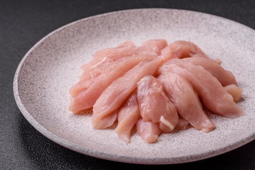Slices of raw chicken or turkey fillet with salt, spices and herbs photo