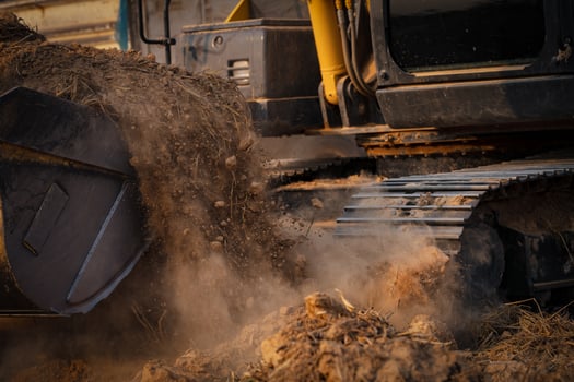 Selective focus on metal bucket teeth of backhoe digging soil. Backhoe working by digging soil at construction site. Crawler excavator digging on soil. Earth moving machine. Excavation vehicle. photo