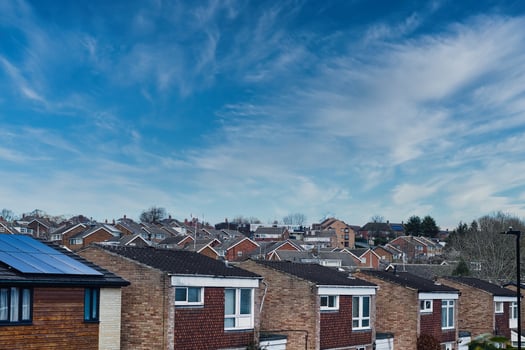 Suburban skyline with rows of houses and solar panels on a roof under a blue sky with wispy clouds in Harrogate, North Yorkshire. photo
