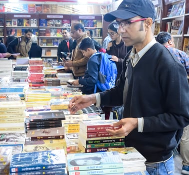 Delhi, India, February 17 2024 - Various age group people reading variety of Books on shelf inside a book-stall at Delhi International Book Fair, Books in Annual Book Fair at Bharat Mandapam complex photo