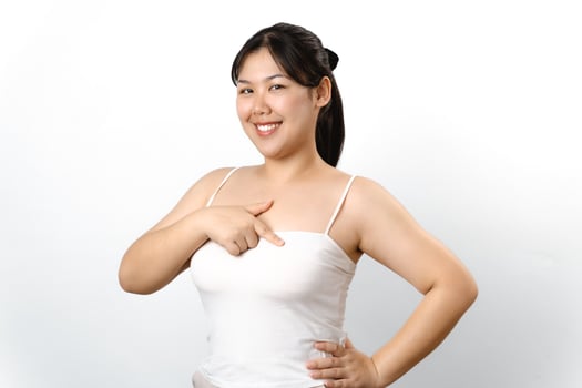 Asian woman checking lumps on her breast for signs of breast cancer on white background. photo