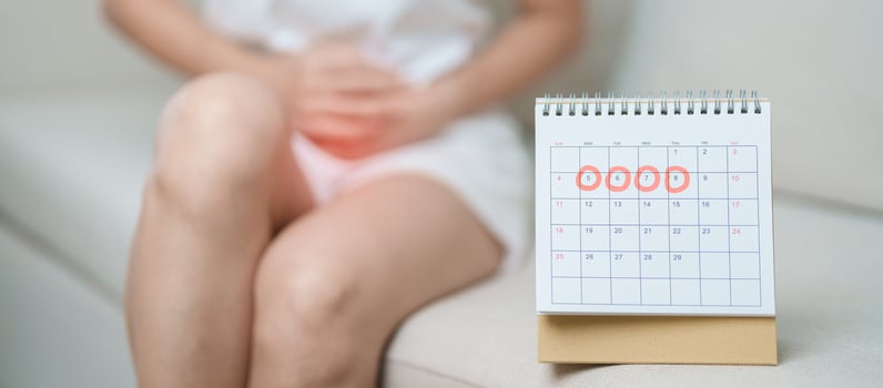 Menstruation period cycle of monthly and Stomachache concepts. woman having abdomen pain with calendar, illness female suffer from premenstrual ache and body Health problem on sofa at home photo
