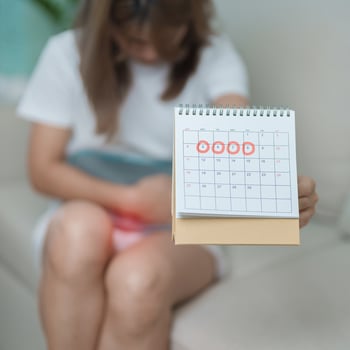 Menstruation period cycle of monthly and Stomachache concepts. woman having abdomen pain with hot water bottle and calendar, illness female suffer from premenstrual ache and body Health problem photo