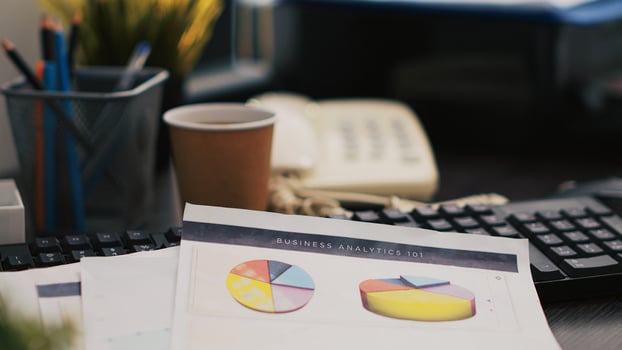 Audit report on desk next to paper cup of coffee in empty accounting department office, close up shot. Clipboard with papers containing economic graphs and figures near hot beverage on table photo