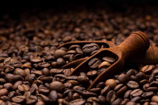 Pile of coffee beans with wooden scoop, close up, dark background with copy space, shallow depth of field photo