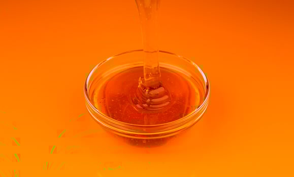 Pouring honey isolated on gold colored background with clipping path photo