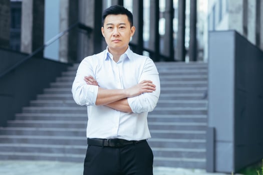 Portrait of serious asian businessman, man outside office looking at camera photo