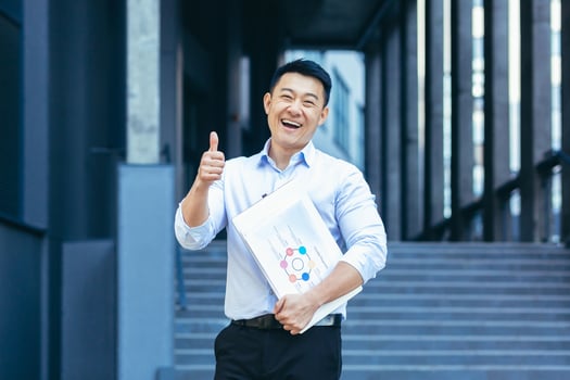 Successful asian businessman outside office smiling, thumbs up affirmatively photo