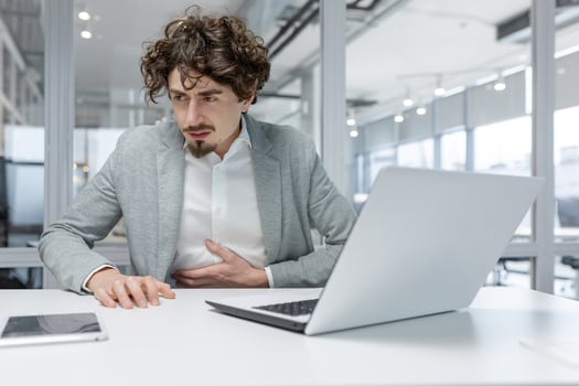 Adult businessman feeling unwell at his workplace in a modern office, showcasing typical office work attributes and indicating stress. photo