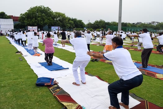 New Delhi, India, June 21, 2023 - Group Yoga exercise session for people at Yamuna Sports Complex in Delhi on International Yoga Day, Big group of adults attending yoga class in cricket stadium photo